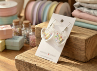 Close-up of heart sprinkle earrings on wooden display showing pastel bead detail