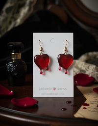 Red dripping heart resin earrings displayed on a white Kaboodle Designs card with rose petals