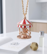 Gold carousel pendant necklace with red and white enamel canopy and four horses, hanging view