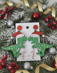 Acrylic Christmas dinosaur earrings on card, green glitter T-rex in Santa hat with candy cane charm and red stud top