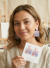 Close-up of model wearing pastel heart and dotted square drop earrings