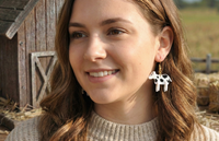 Close-up of black and white cow earring worn on model's ear