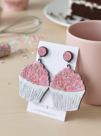 Close-up of cupcake earrings on backing card showing sprinkle detail and pink stud tops