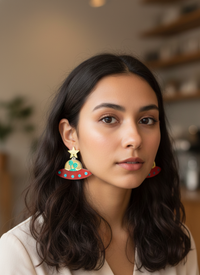 Close-up of alien UFO earring worn on model's ear showing gold and red detail