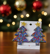 Pair of Christmas tree drop earrings on Kaboodle Designs card in front of Christmas tree lights