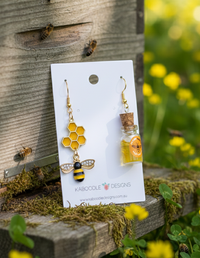 Mismatched bee and honeycomb earrings on card, with honey jar earring and dipper alongside