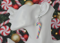 Close-up of rainbow candy cane earring worn on ear against Christmas background