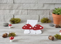 Red toadstool acrylic earrings on card, styled with acorns, moss and a small succulent