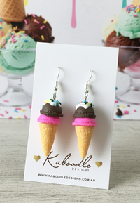 Pair of resin ice cream cone earrings with chocolate dip, pink base and rainbow sprinkles on display card