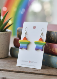 Close-up angle of rainbow star earrings showing glossy resin stripes and star shape