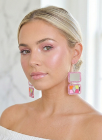 Close-up of makeup palette earring worn on model's ear showing mirror and eyeshadow detail