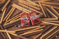 Close-up of Pocky earrings resting on a pile of chocolate and biscuit Pocky sticks