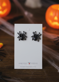 Black spider stud earrings on a Kaboodle Designs card with Halloween pumpkin decorations