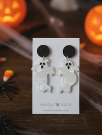 White resin ghost drop earrings with black glitter stud tops on a Kaboodle card, styled with pumpkins
