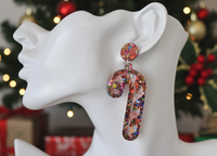 Close-up of candy cane earring worn on ear showing glitter confetti detail