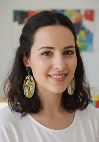 Woman wearing mustard yellow leaf-pattern statement earrings with black stud tops, close-up view
