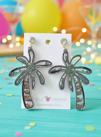Black-outlined acrylic palm tree shaker earrings with green and gold beads, on card