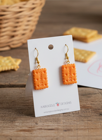 Orange resin biscuit drop earrings on a Kaboodle Designs earring card