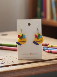 Yellow resin crayon box earrings with red, green and blue crayons, shown on jewellery card