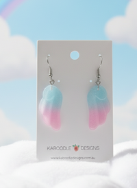 Pastel blue and pink ombre resin angel wing earrings displayed on Kaboodle Designs card