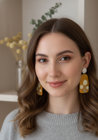 Woman wearing mustard billy button flower drop earrings, close-up side view