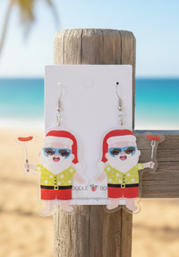 Acrylic drop earrings of beach Santa in sunglasses and floral shirt holding a sausage on a fork, shown on card