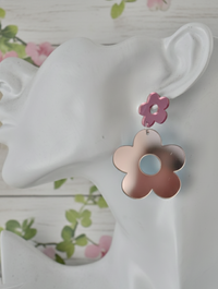 Close-up of mirrored pink daisy earring worn on a display ear, showing reflective finish