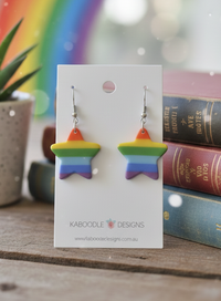 Rainbow striped star drop earrings on a Kaboodle Designs card with books and rainbow backdrop
