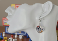 Close-up of transparent dice earring worn on ear, showing coloured dot detail