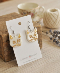 Pair of cat face drop earrings on card, angled view showing gold linework