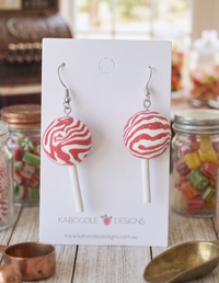 Pink and white peppermint swirl lollipop resin drop earrings on a Kaboodle Designs card