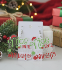 Clear acrylic drop earrings on card reading 'Nice Until Proven Naughty' with Santa hat and holly detail
