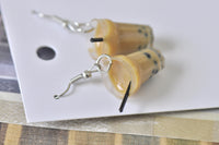 Close-up angled view of boba earrings showing glossy resin cup, black pearls and straw detail
