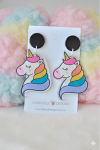 Acrylic rainbow unicorn drop earrings on black studs, shown on Kaboodle Designs card