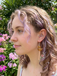 Close-up of duck lollipop earring worn on ear, showing glittery resin duck and peach stick