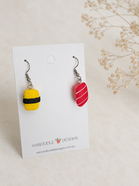 Resin sushi nigiri earrings on card: yellow tamago egg and red salmon piece