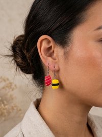 Close-up of mismatched sushi earrings worn on ear, showing textured resin detail