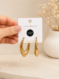 Hand holding gold teardrop hoop earrings on a Kaboodle Designs display card