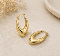 Pair of gold plated teardrop hoop earrings laid flat on a stone surface