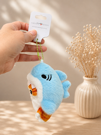 Side view of blue shark plush keychain showing fin and winking eye design