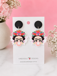 Acrylic drop earrings on card featuring a flower-crowned face blowing pink bubble gum, black stud tops