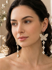 Woman wearing gold rhinestone butterfly earring with long crystal cluster drop, side view