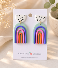 Clay rainbow drop earrings on card, speckled white tops with sage, blue, pink and orange arches