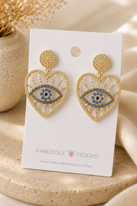 Gold evil eye heart earrings with rhinestone detail displayed on Kaboodle Designs card