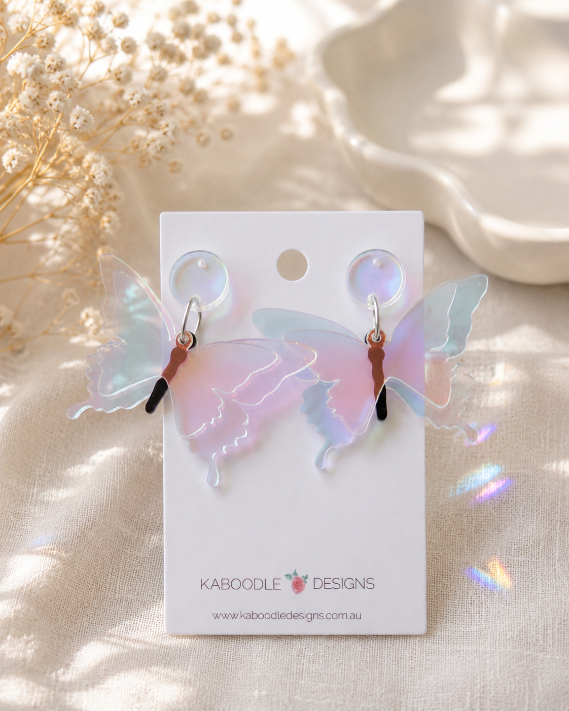 Pair of iridescent Perspex butterfly drop earrings on a Kaboodle Designs card