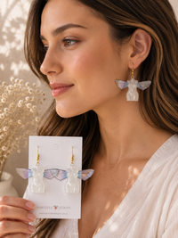 Close-up of butterfly wing torso earring worn on model's ear, showing gold-flecked wing detail