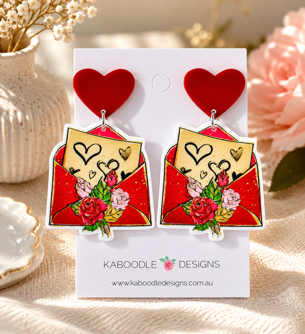 Red heart stud earrings with printed love letter envelope and rose charm on card