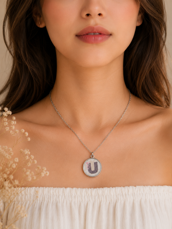 Letter U resin pendant necklace worn on model's neckline over white top