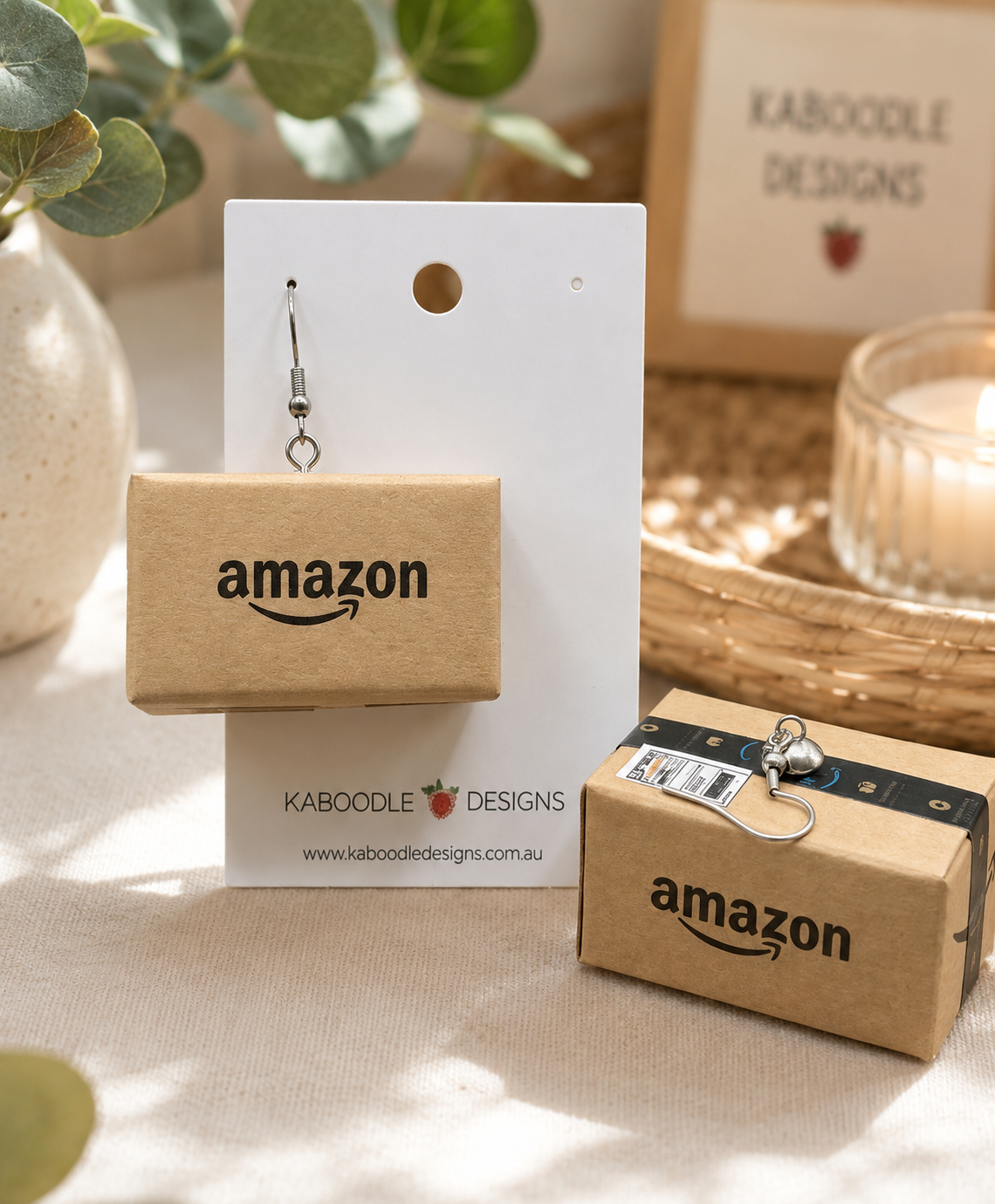 Miniature Amazon parcel drop earring on white display card with Kaboodle Designs branding, second box shown beside with