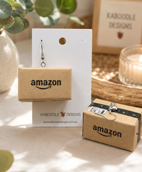 Miniature Amazon parcel drop earring on white display card with Kaboodle Designs branding, second box shown beside with